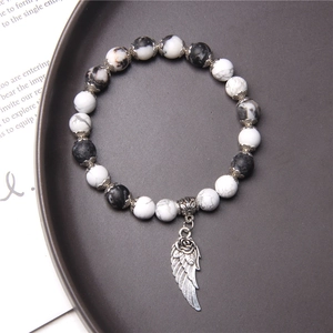 Minimalist beaded bracelet with black and white marbled stones and a silver wing pendant