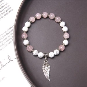 Detailed close-up of pink crystal and turquoise bead bracelet with silver wing charm