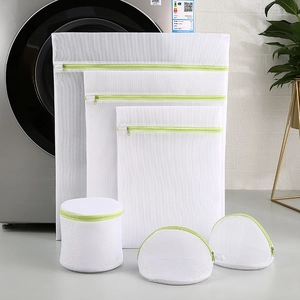 Detail view of 6-piece white mesh laundry bag set with green zippers for washing machines