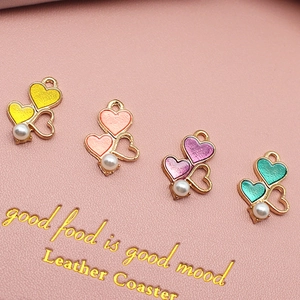 DIY heart enamel charms with gold frames and pearl accents on pink leather