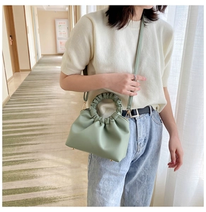 Detail of light green cloud bag with pleated handle and strap worn by a model