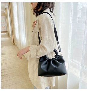 Detail of black pleated cloud handbag with elastic handle and golden protective metal feet