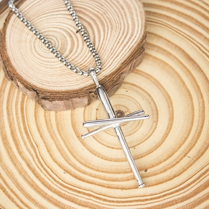 Close-up of silver stainless steel baseball bat cross pendant on a rustic wood background