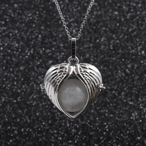 Detail of stainless steel necklace with heart-shaped angel wings and white bead