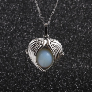 Stainless steel necklace featuring angel wing pendant and white bead on black background