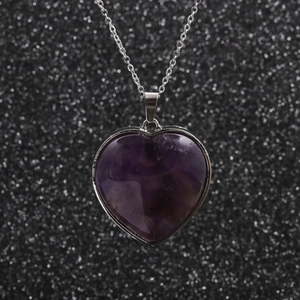 Minimalist stainless steel necklace with purple heart pendant on a dark background