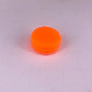 Detailed view of an orange macaron-shaped plastic cosmetic cream jar on a purple surface