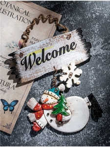 Close-up of vintage snowman welcome sign with snowflake accents on dark rustic wall