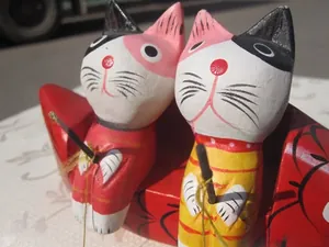 Detail of hand-painted wooden cat figurines in fishing pose with vibrant folk art style