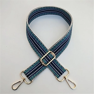 Close-up of ethnic geometric pattern wide strap with polished gold-tone metal hooks
