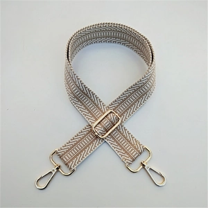 Close-up of adjustable woven strap with beige chevron pattern and gold metal hooks