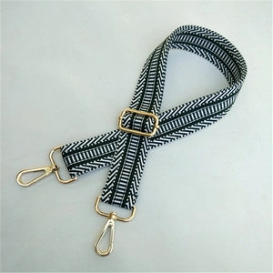 Close-up of adjustable geometric strap with black and white patterns and gold hardware