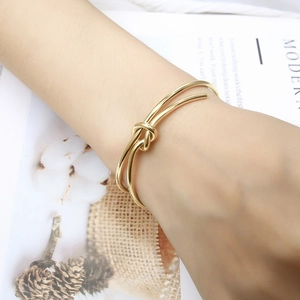 Detailed close-up of 18K gold-plated knotted bracelet on a female wrist