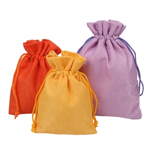 Three colorful linen drawstring pouches in orange, yellow, and purple for jewelry storage