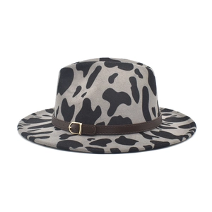 Close-up of cow print felt fedora with a dark brown faux leather band and buckle