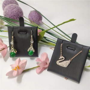 Close-up of rose gold swan necklace with crystals and green bead earrings on black card
