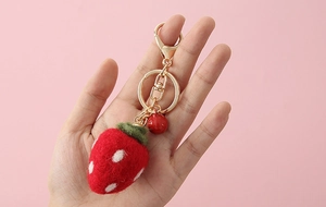 Close-up of strawberry felt keychain with gold clasp, red bell and cute white dots