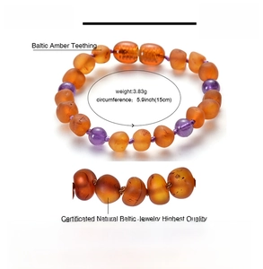 Detail of Baltic amber teething bracelet with orange beads and purple amethyst stones