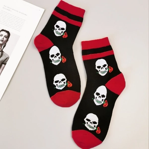 Détail de chaussettes d'Halloween avec crânes blancs et roses rouges sur coton noir de qualité