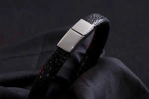 Macro detail of men's black textured leather bracelet with polished silver metal buckle
