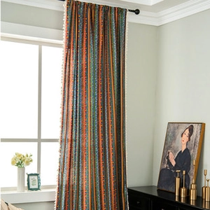 Detail of colorful striped cotton linen curtain featuring delicate white pom-pom trim edge