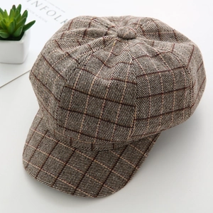 Detailed texture of brown checkered newsboy cap made of wool blend on white backdrop