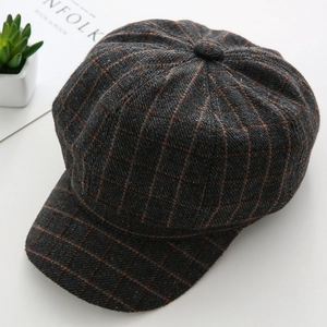 Detail shot of grey checked wool newsboy cap with orange stripes on white desk