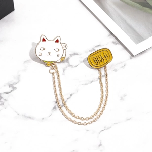 Cute Japanese cartoon cat brooch with gold chains and oval enamel badge on marble