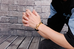 Detailed view of men's leather bracelet with bullet-shaped gold clasp on wrist