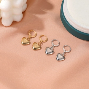 Boucles d'oreilles cœur polies en or et argent avec créoles sur fond de satin soyeux