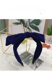 Close-up of a wide velvet headband with a large dark blue bow and non-slip lining