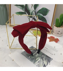 Close-up of a red velvet headband with large double bow on a gold display stand