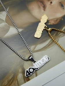 Détail des colliers 404MOB dorés et argentés avec pendentifs sur un magazine de mode