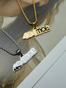 Détail macro des pendentifs logo 404MOB en acier inoxydable doré et argenté