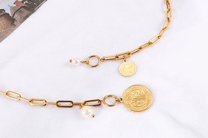 Détail du collier en titane doré avec perles blanches et médailles de Saint-Benoît