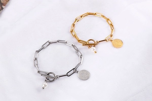 Détails des bracelets dorés et argentés avec perles et breloques de Saint-Benoît