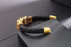 Dettaglio del bracciale in pelle intrecciata nera con testa di leone d'oro sulla scatola