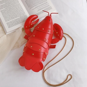 Creative red lobster shaped crossbody bag with gold metal chain strap on white fabric