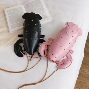 Detail of lobster-shaped crossbody bags in black and pink with gold studs and chain strap