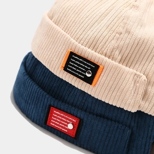 Detail of corduroy docker hats in beige and blue showing fabric texture and metal rivets