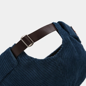 Detail of blue corduroy brimless docker hat with adjustable brown leather strap and metal buckle