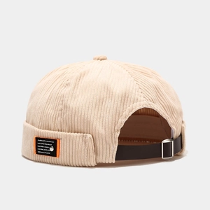 Detail of beige corduroy docker hat featuring adjustable leather strap and metal buckle