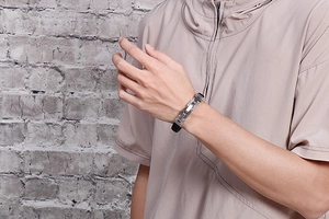 Close-up of men's braided steel and black silicone bracelet worn on a wrist