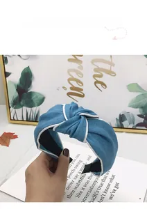 Close-up of a blue denim headband with center knot and white contrast stitch detail