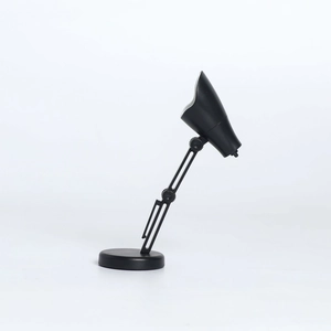 Gros plan d'une mini lampe de bureau LED noire avec joints réglables et pliable