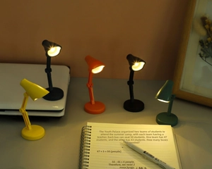 Détail de mini lampes LED à clip colorées sur un bureau diffusant une lumière chaude