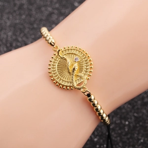 Detail of snake charm bracelet with gold beads, black cord and white zircon stone