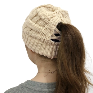 Detail of cream cable knit ponytail beanie with rear opening for hair display