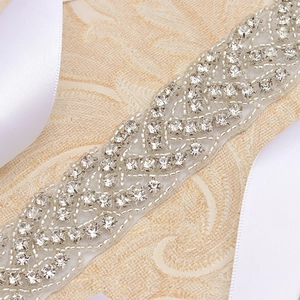 Detail of bridal sash featuring sparkling rhinestones and white ribbon on ivory fabric
