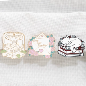 Three-piece enamel pin set featuring Book Lover, Dear Peter Kavinsky letter, and cute cat